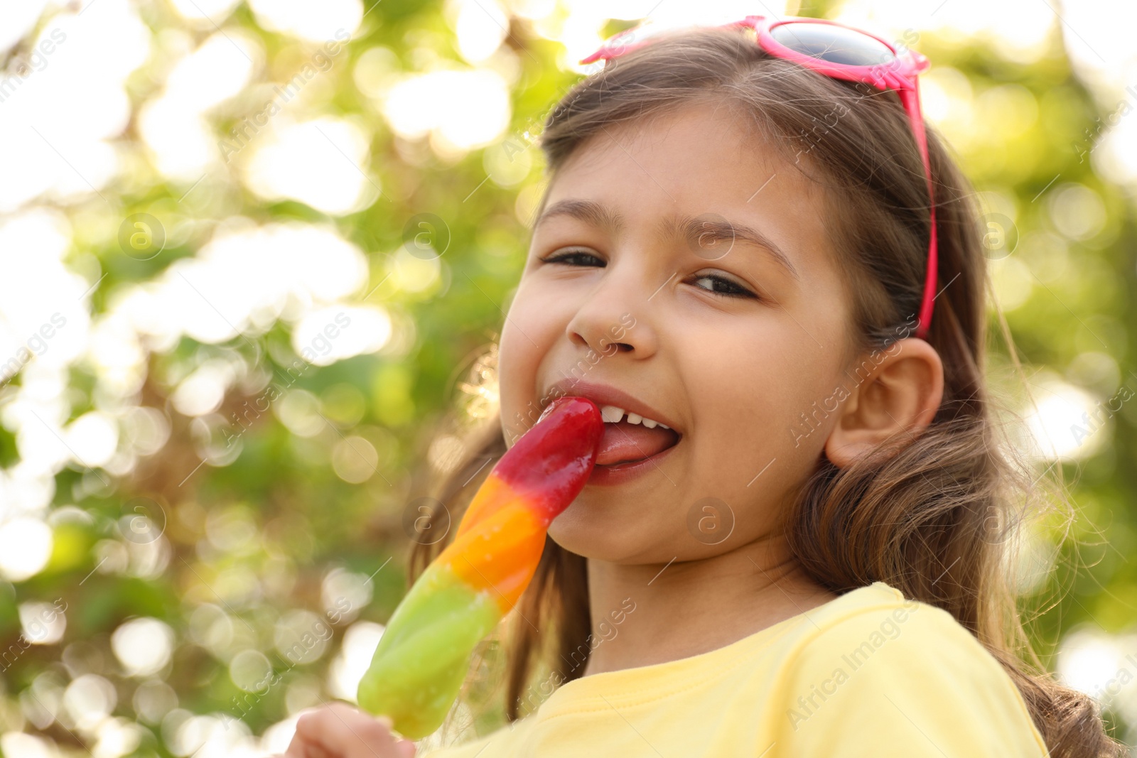 Photo of Cute little girl with delicious ice cream outdoors, low angle view