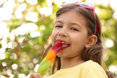 Photo of Cute little girl with delicious ice cream outdoors, low angle view