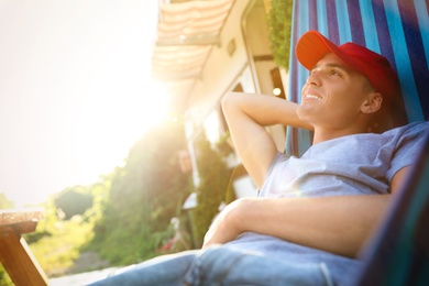 Photo of Young man resting in hammock near motorhome outdoors on sunny day