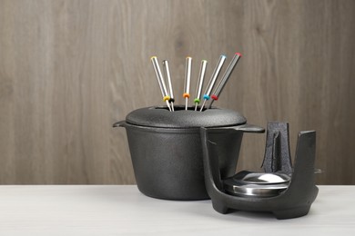 Photo of Fondue set on white wooden table, space for text