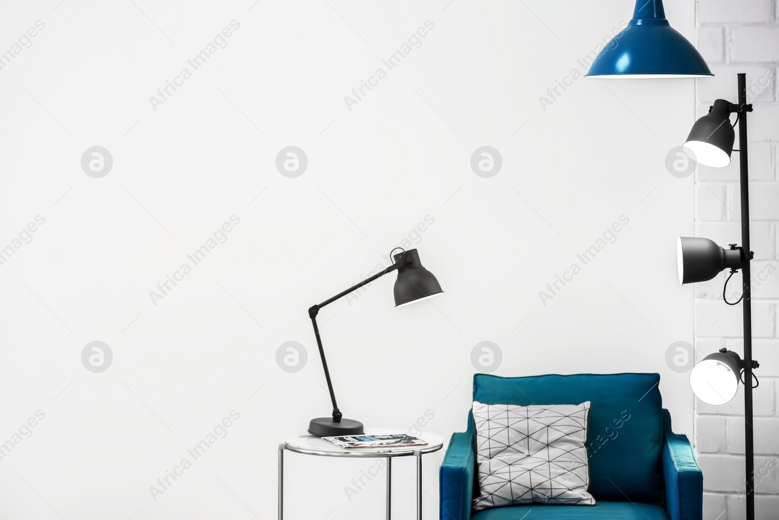 Photo of Modern lamps with blue armchair indoors