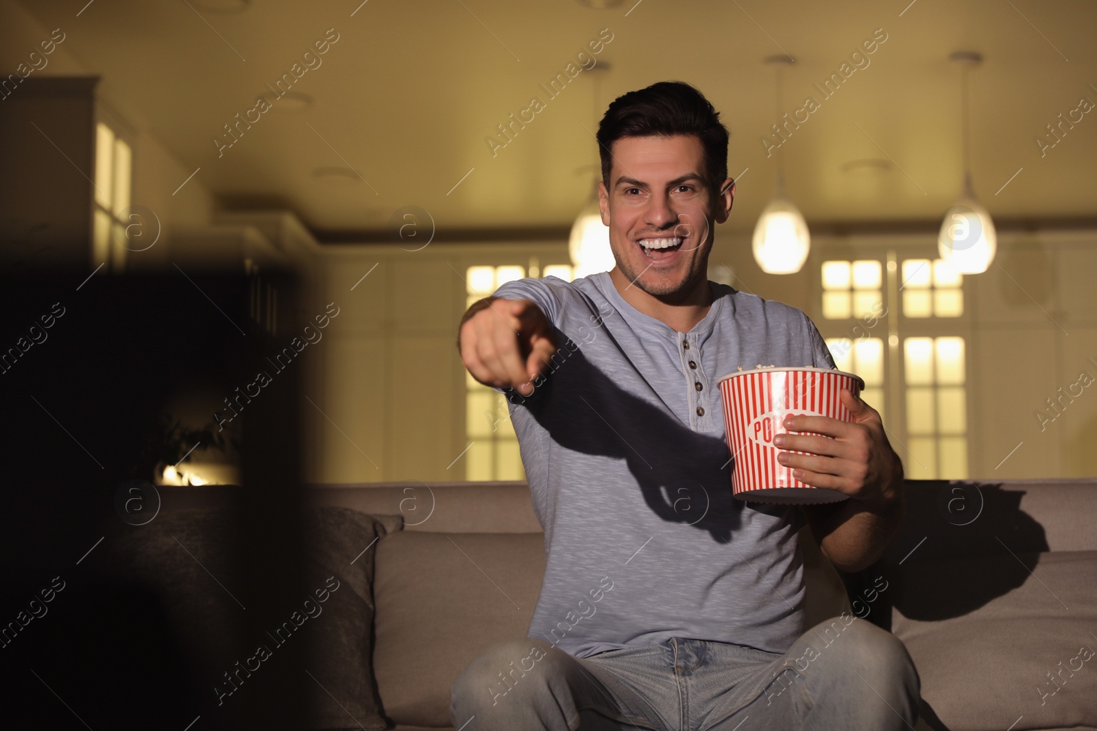 Photo of Man watching movie with popcorn on sofa at night