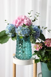 Photo of Beautiful hortensia flowers in vase on stand indoors