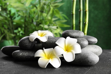 Photo of Zen stones and exotic flowers on table against blurred background