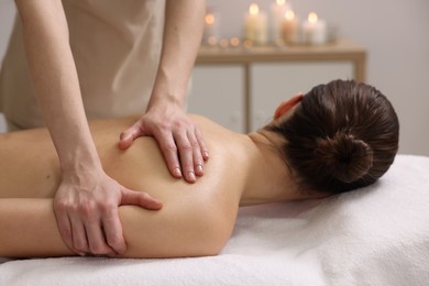 Photo of Woman receiving back massage on couch in spa salon