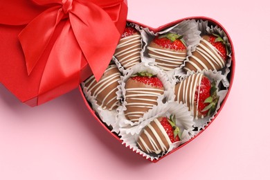 Photo of Heart shaped box with delicious chocolate covered strawberries on pink background, top view