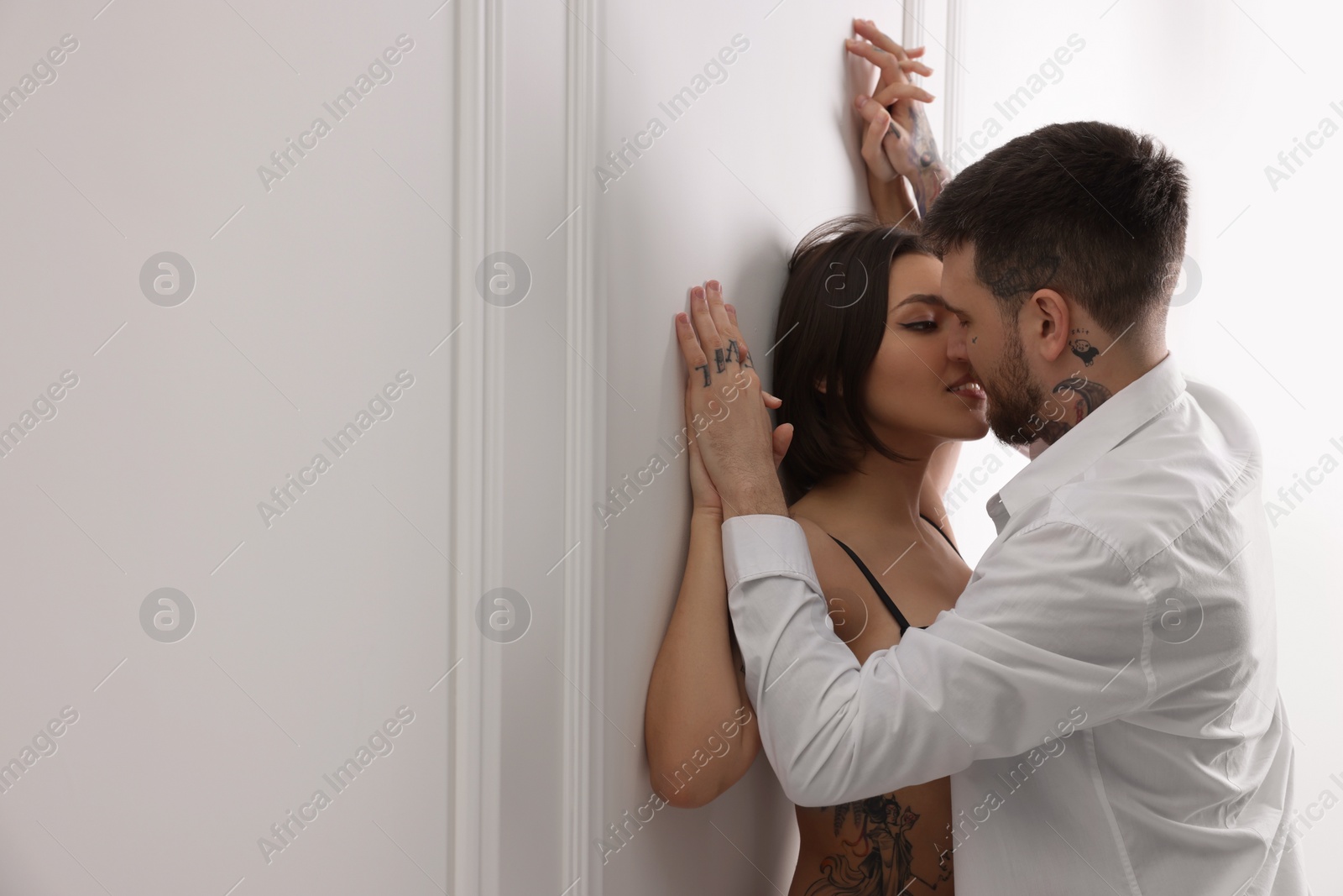 Photo of Passionate couple having sex near white wall indoors, space for text