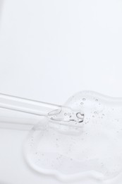 Photo of Dripping cosmetic oil from pipette onto light surface, closeup. Space for text