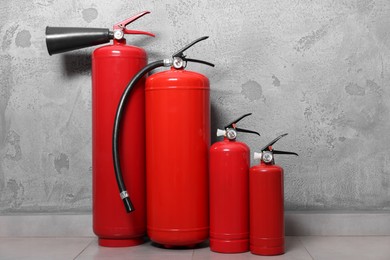 Photo of Four red fire extinguishers near grey wall