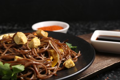 Stir-fry. Tasty noodles with vegetables and meat on dark table, closeup