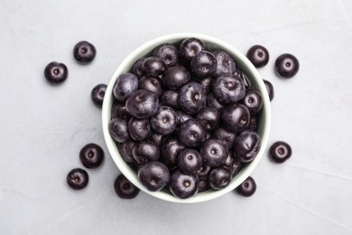 Photo of Bowl of fresh acai berries on light stone table, top view. Space for text