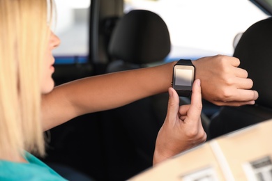 Woman using modern smart watch in car, closeup