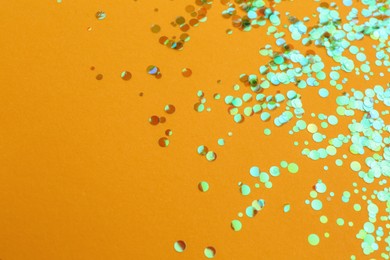 Photo of Shiny bright glitter on orange background. Space for text