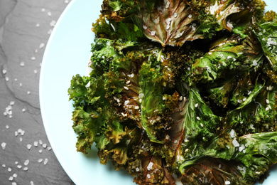 Photo of Tasty baked kale chips on table, closeup