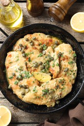 Photo of Delicious chicken piccata with herbs and lemon on wooden table, flat lay