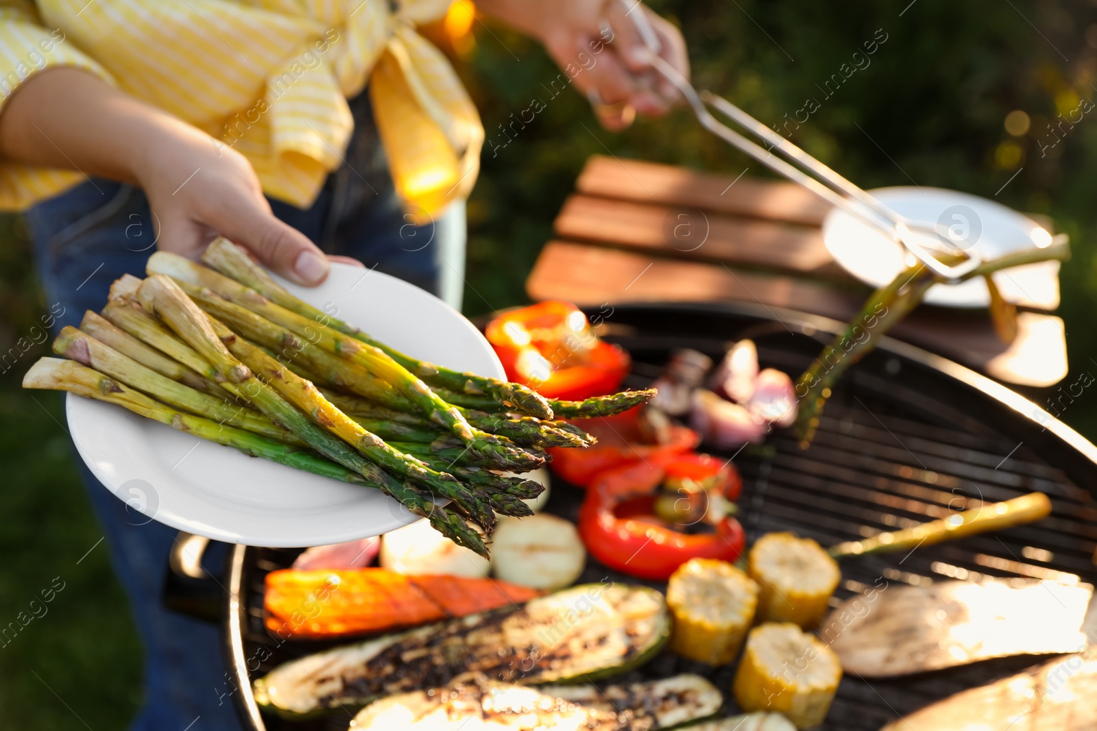 Photo of Woman cooking vegetables on barbecue grill outdoors, closeup