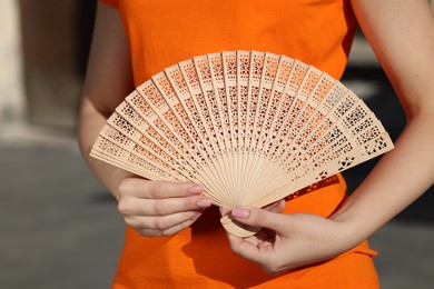 Woman with hand fan outdoors, closeup view