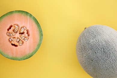 Photo of Whole and cut fresh ripe cantaloupe melons on yellow background, flat lay. Space for text