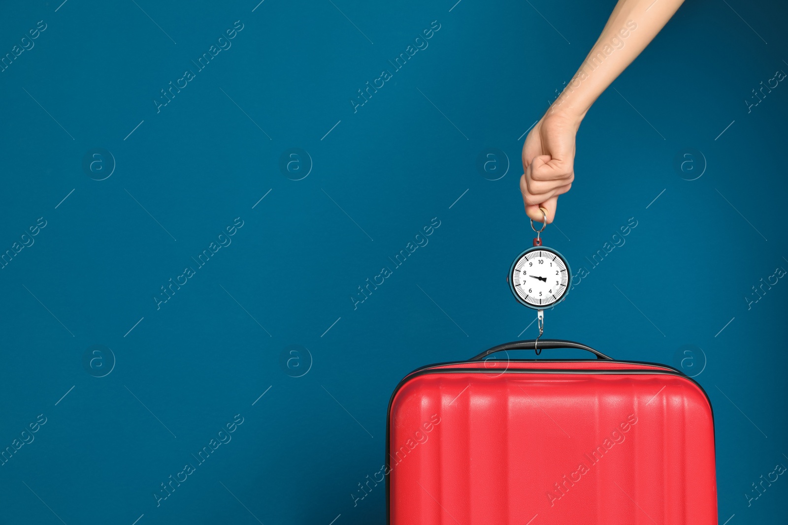 Photo of Woman weighing suitcase against color background, closeup. Space for text