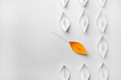 Photo of Yellow paper boat floating to others on white background, flat lay with space for text. Uniqueness concept