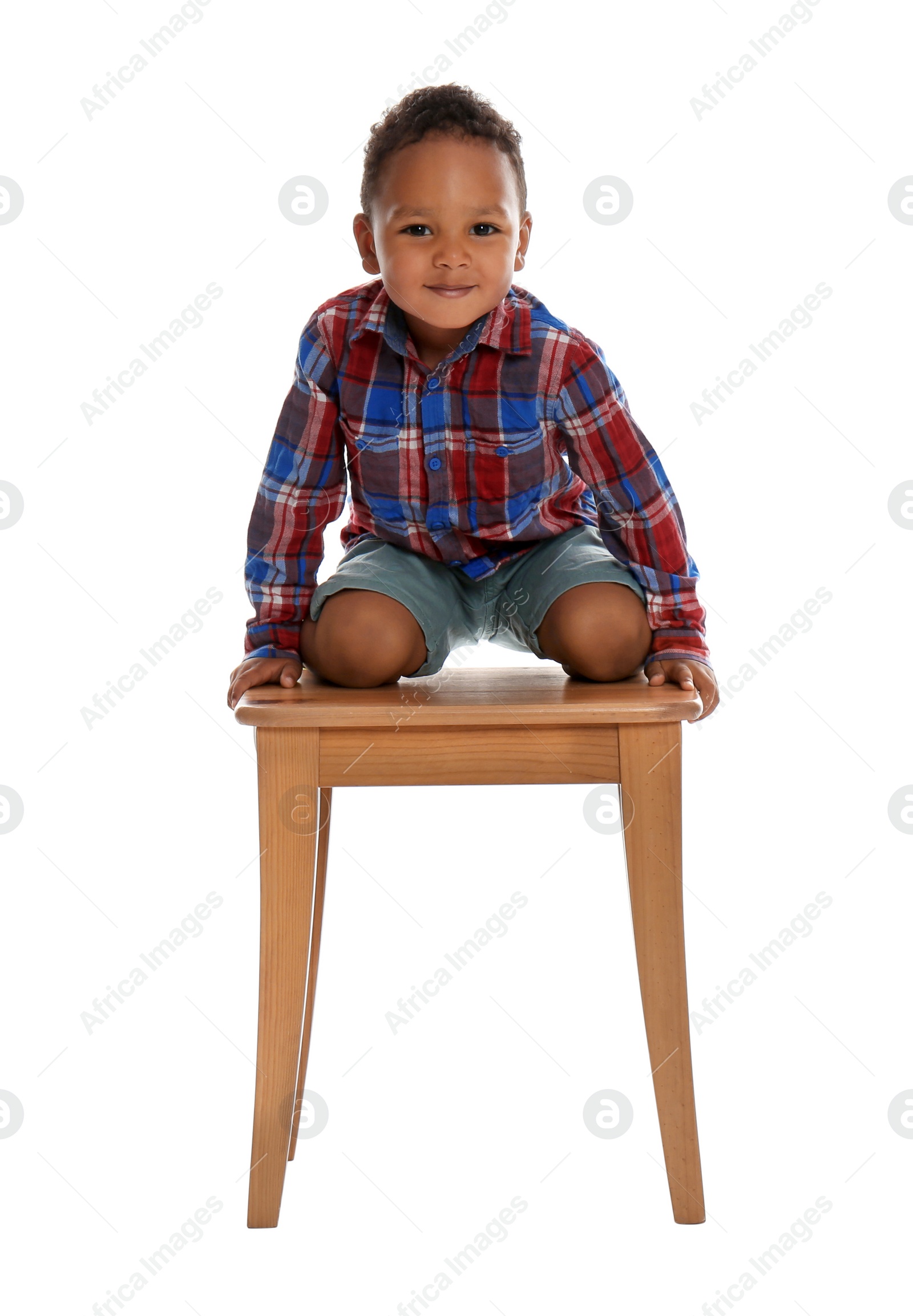 Photo of Little African-American boy climbing up stool on white background. Danger at home