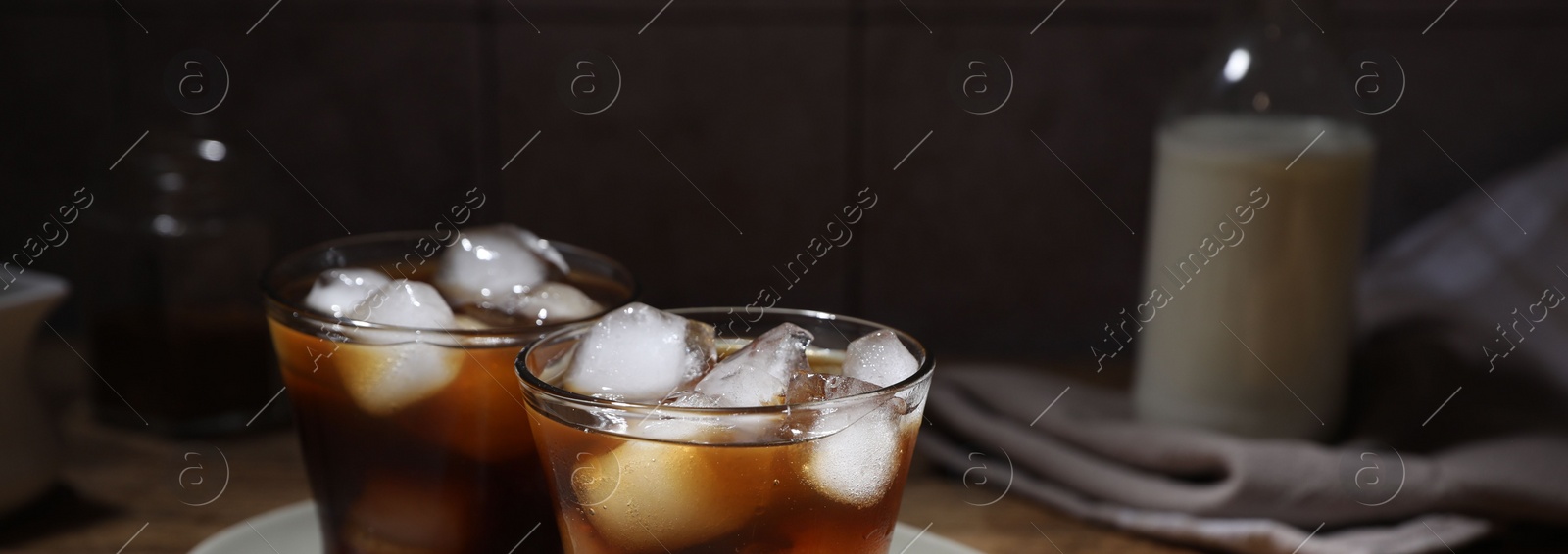 Photo of Refreshing iced coffee in glasses, ingredients and spoon on wooden table