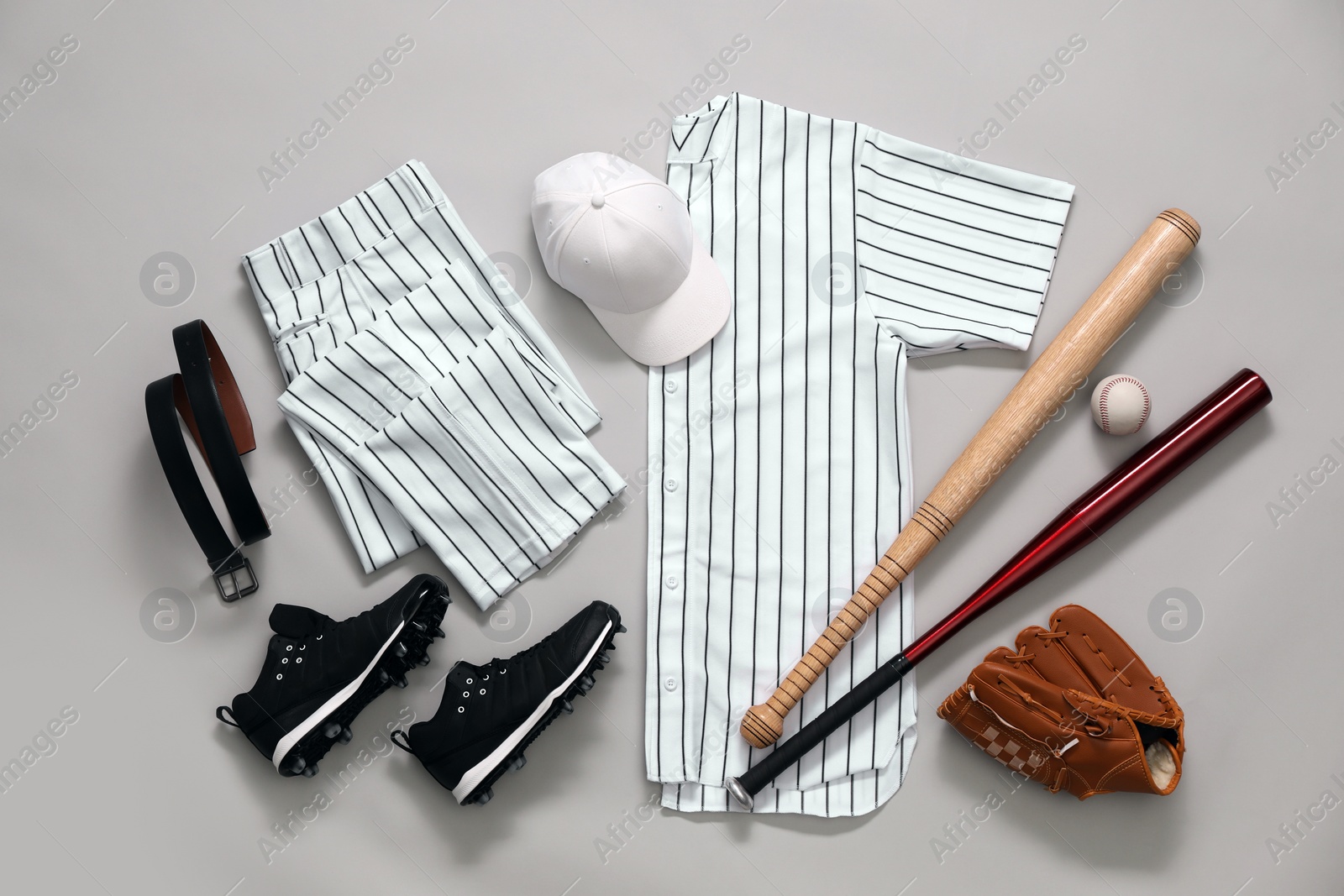 Photo of Baseball uniform and other sports equipment on white background, flat lay