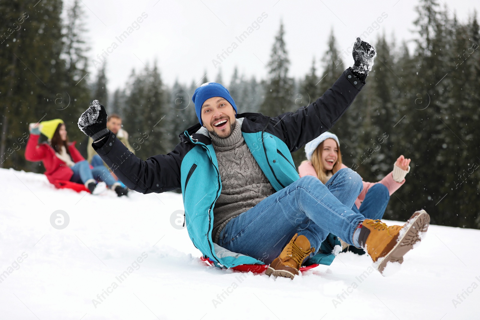 Photo of Happy friends sliding on sleds outdoors. Winter vacation