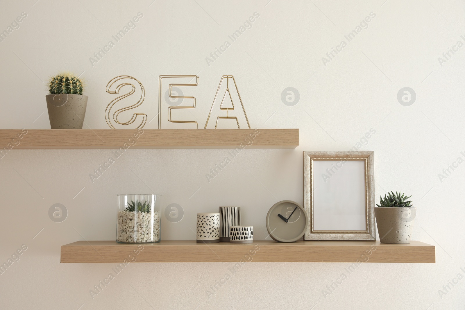 Photo of Wooden shelves with plants and decorative elements on light wall