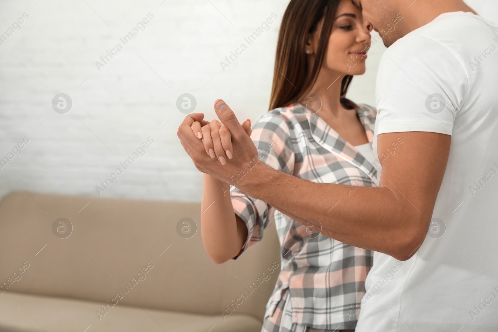 Photo of Happy young couple dancing in living room at home, focus on hands