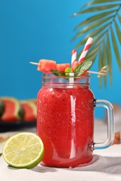 Photo of Tasty watermelon drink with lime in mason jar on sand