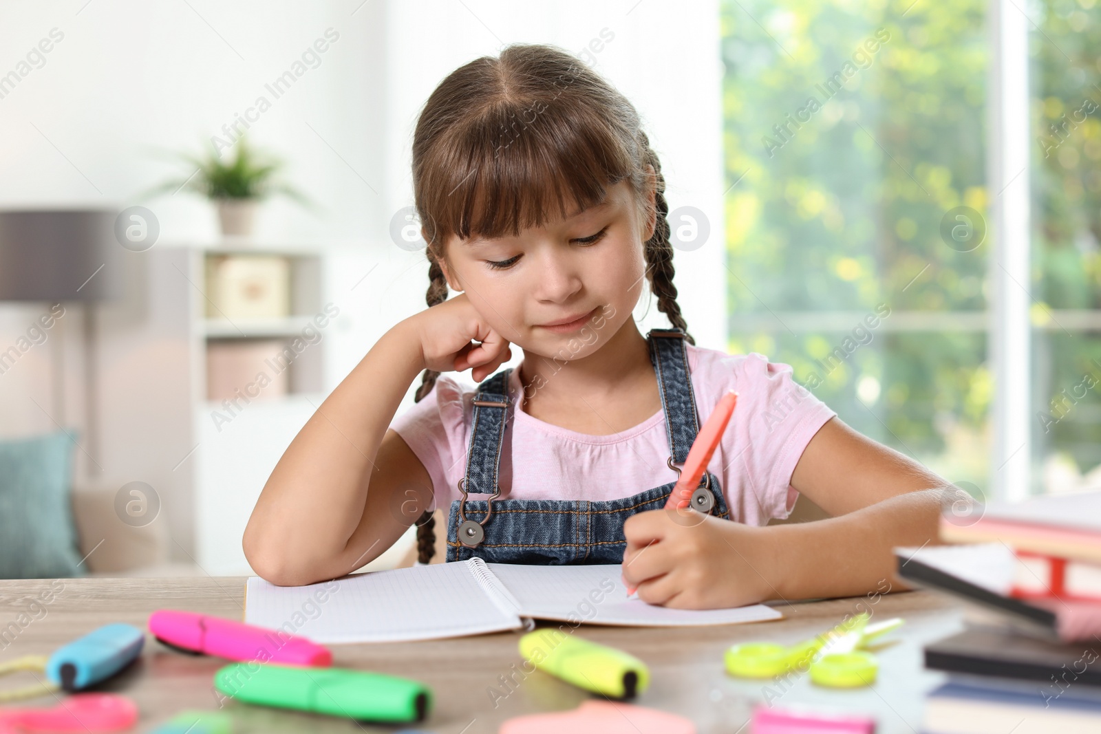 Photo of Little girl doing assignment at home. Stationery for school