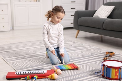 Little girl playing toy xylophone at home