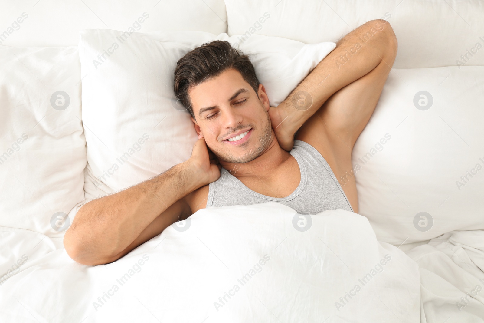 Photo of Man awakening in bed at home, top view. Lazy morning