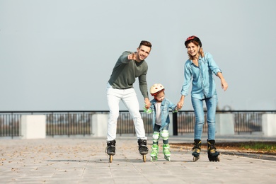 Photo of Happy family roller skating on embankment. Active leisure