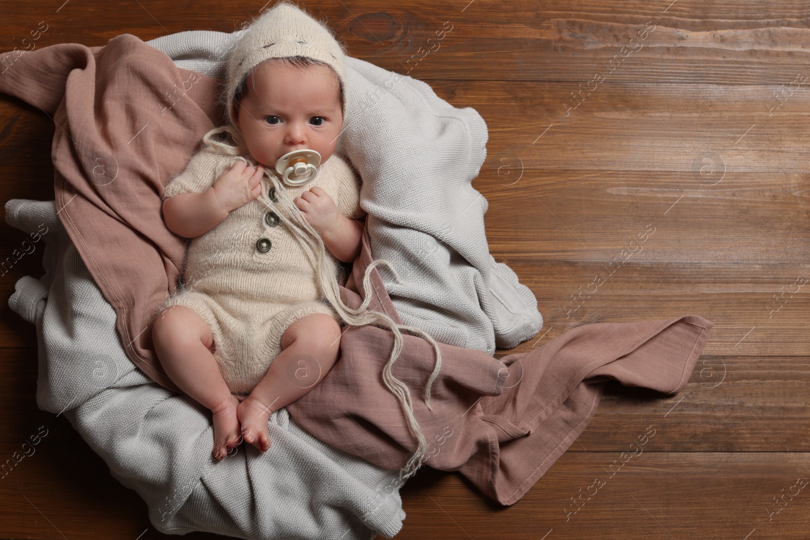 Photo of Cute newborn baby with pacifier on wooden background, top view. Space for text