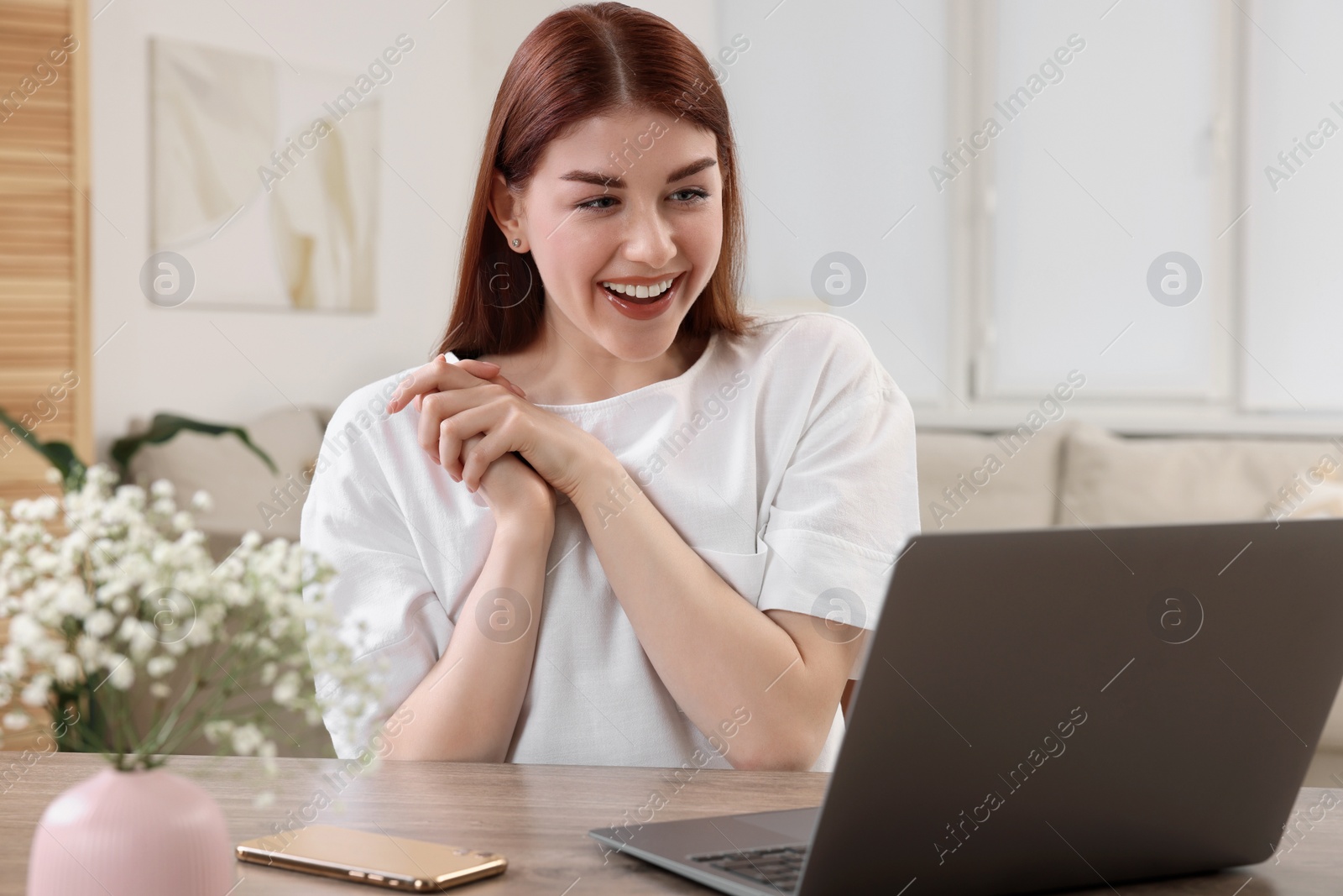 Photo of Happy woman with laptop at table in room