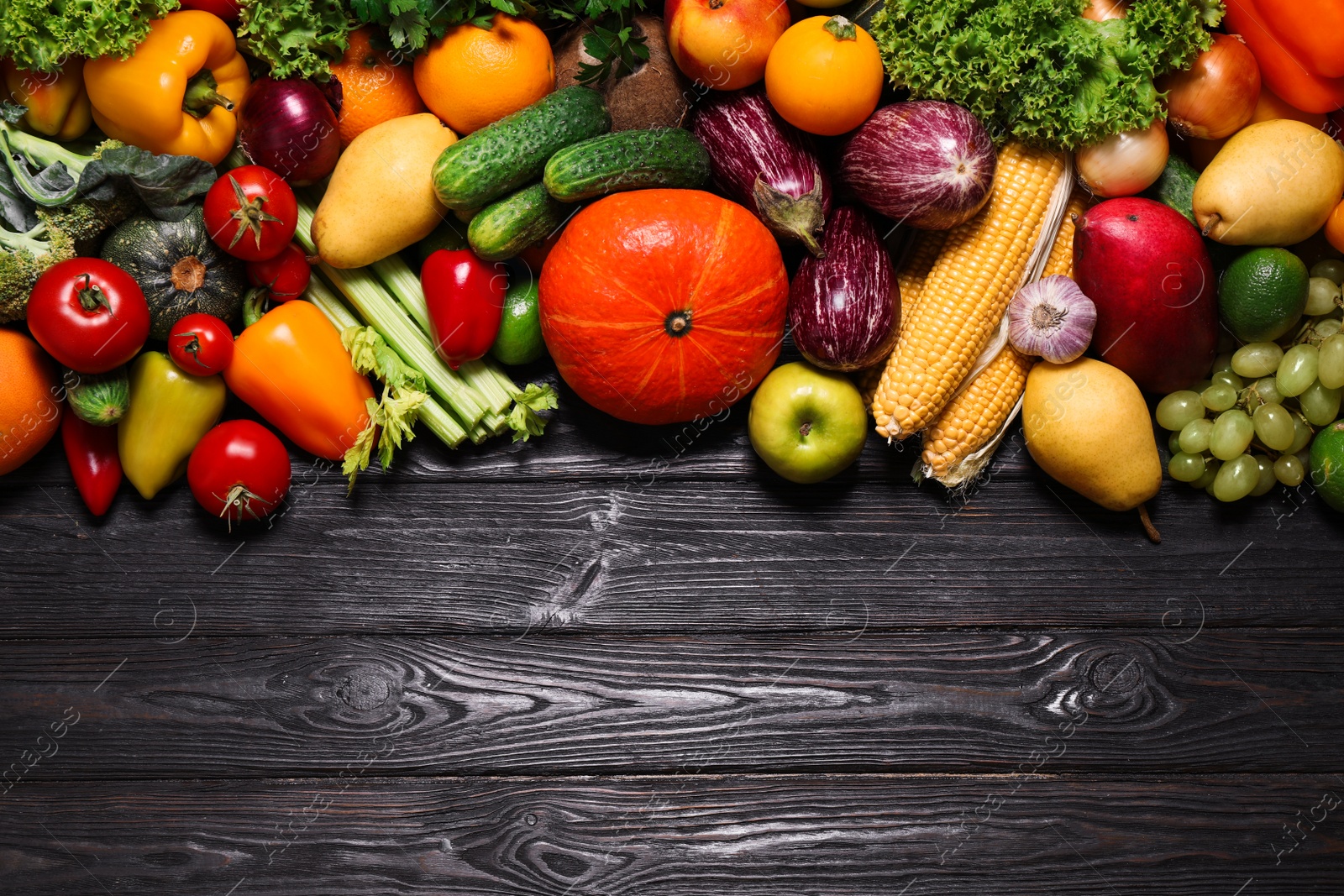 Photo of Assortment of fresh organic fruits and vegetables on black wooden table, flat lay. Space for text