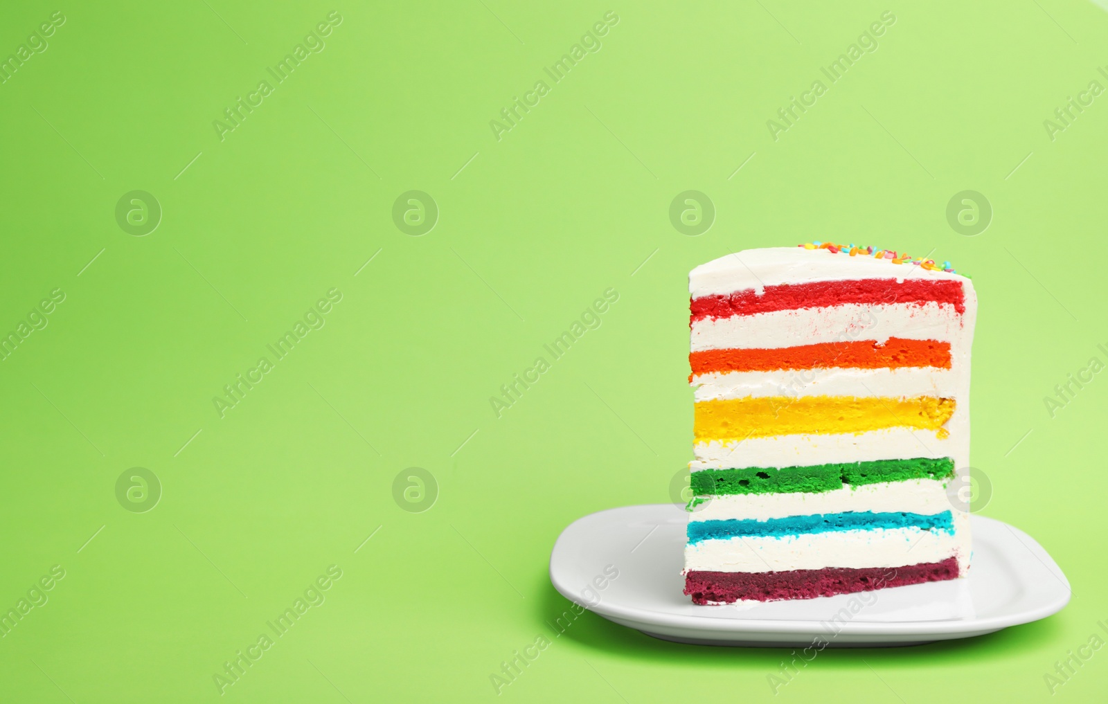 Photo of Slice of delicious rainbow cake on color background