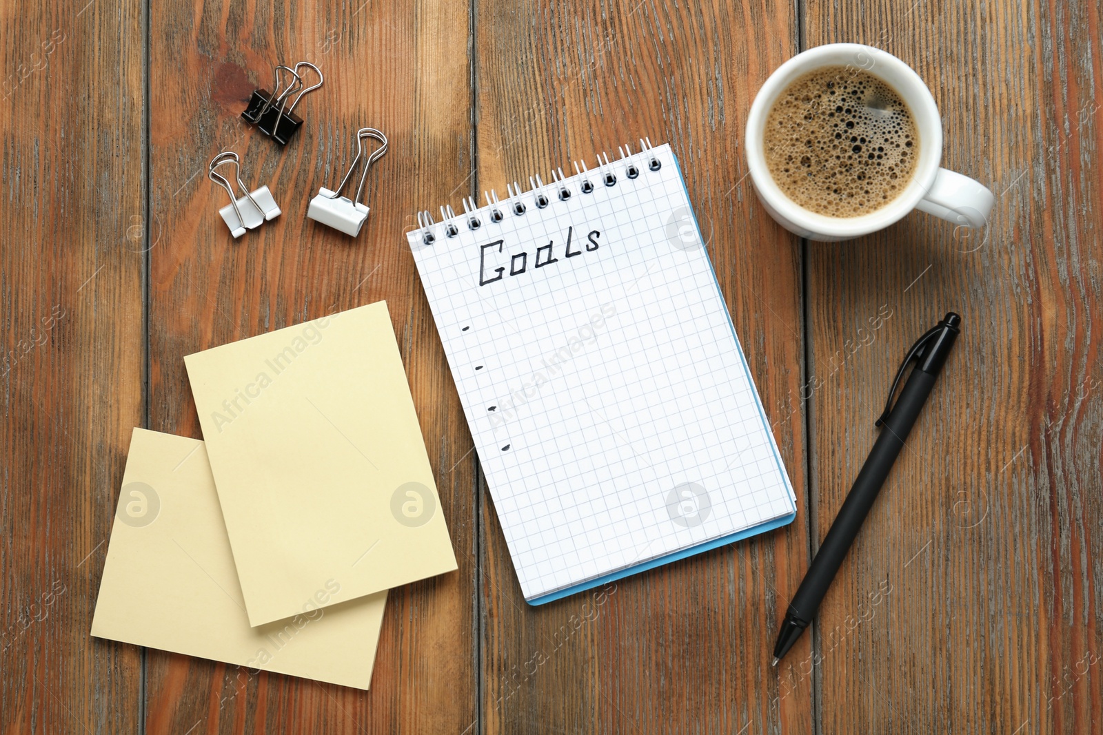 Photo of Flat lay composition with notebook and cup of coffee on wooden table. Goals for New Year 2021