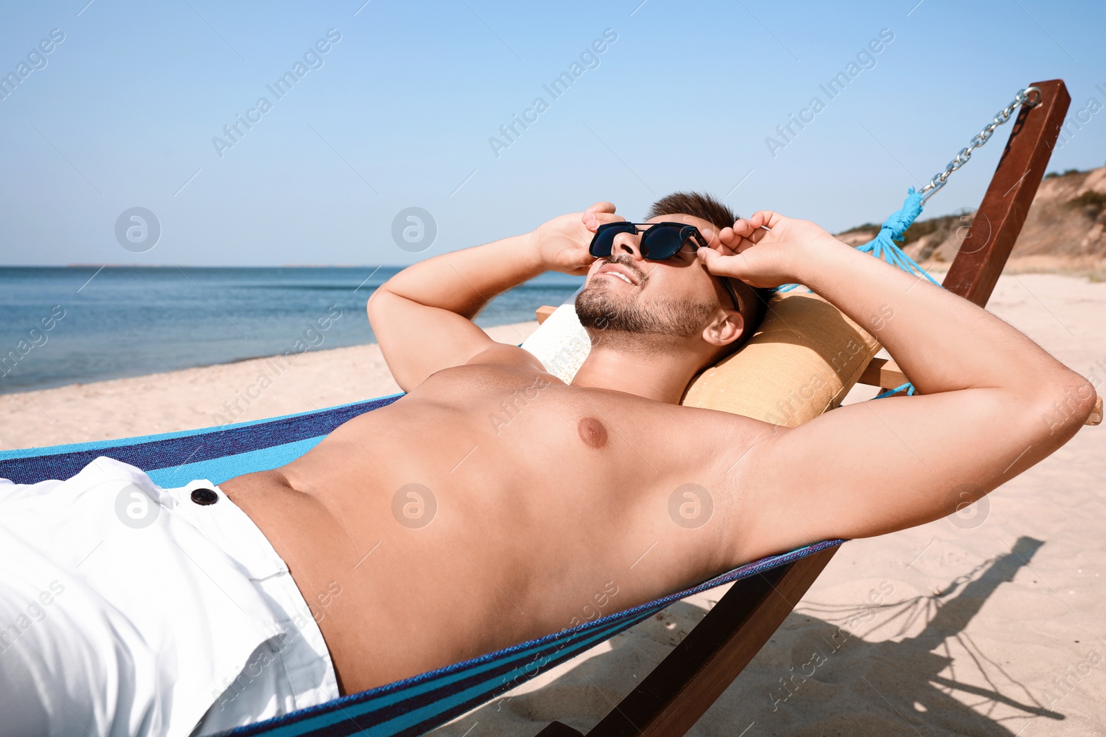 Photo of Young man relaxing in hammock on beach