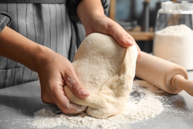 Photo of Woman kneading dough for pastry on table