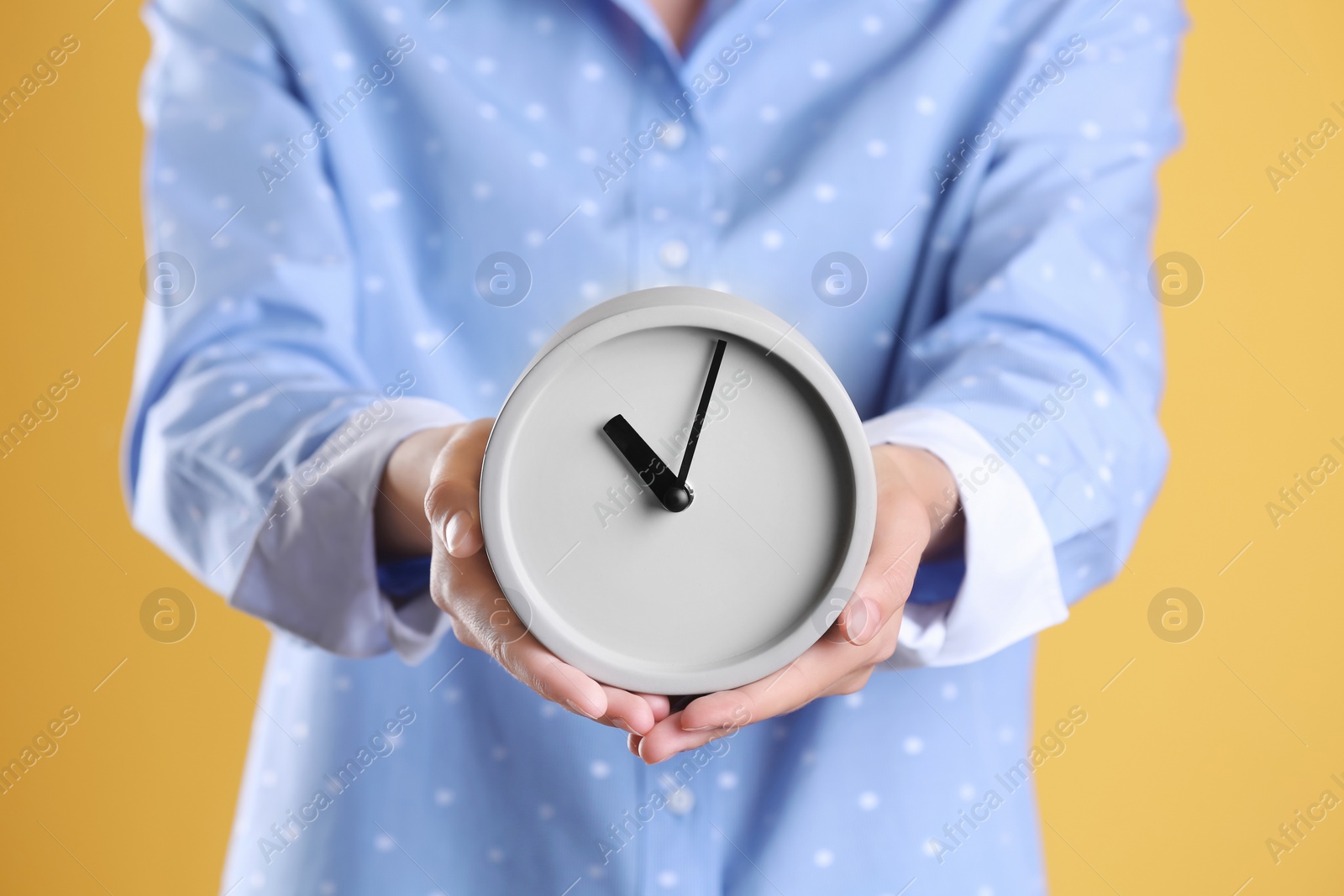 Photo of Young woman holding alarm clock on color background. Time concept