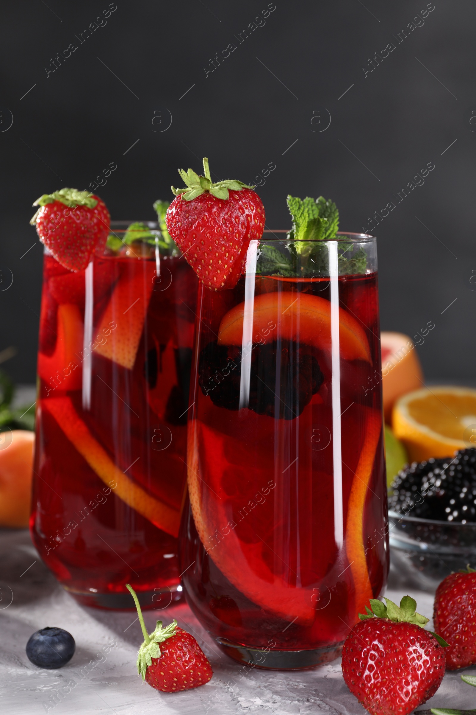 Photo of Delicious refreshing sangria and ingredients on light grey table, closeup