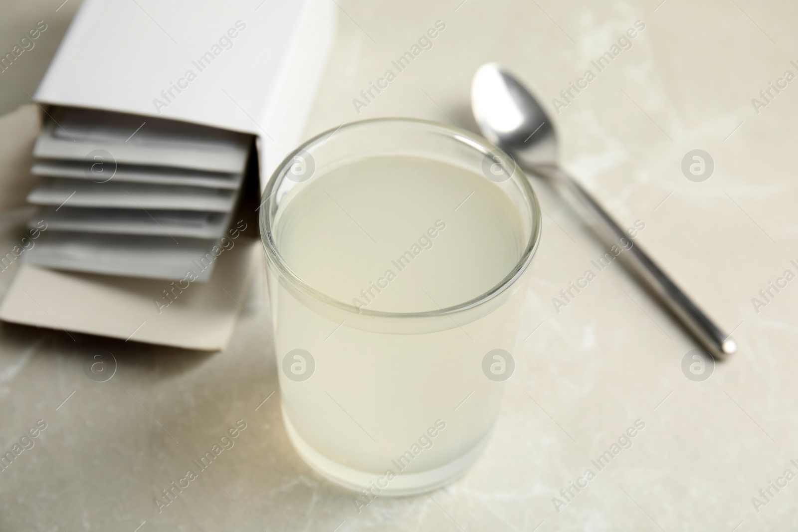 Photo of Medicine sachets, glass of water and spoon on light table