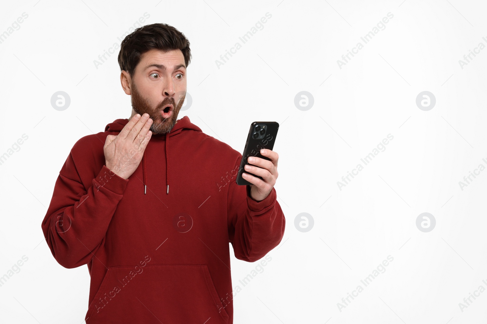 Photo of Surprised man with smartphone on white background. Space for text