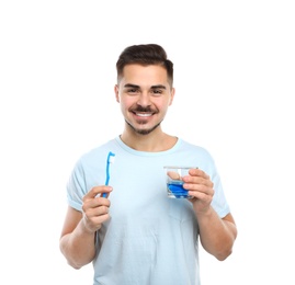 Photo of Young man holding toothbrush and glass with mouthwash on white background. Teeth care