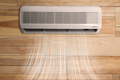 Image of Modern air conditioner on wooden wall indoors