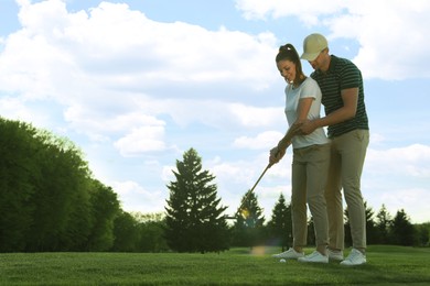 Photo of Man teaching his girlfriend to play golf on green course