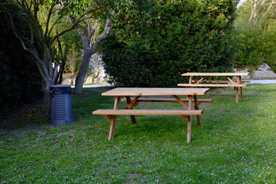 Photo of Wooden benches and tables on green grass in recreational area